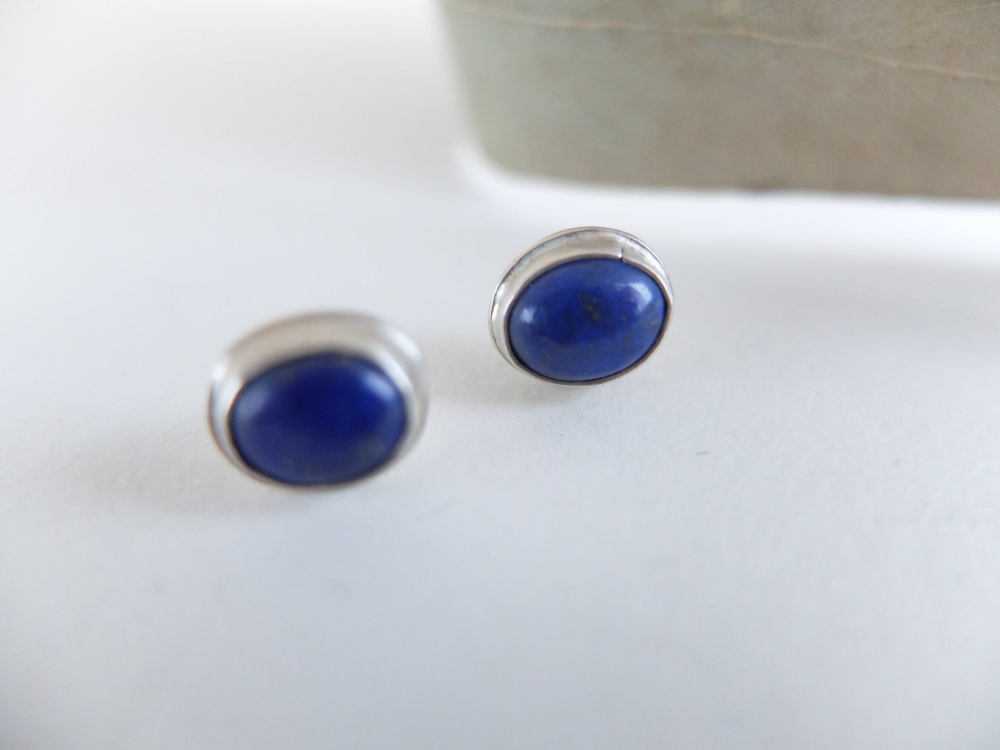Pair of blue oval earrings on a white surface