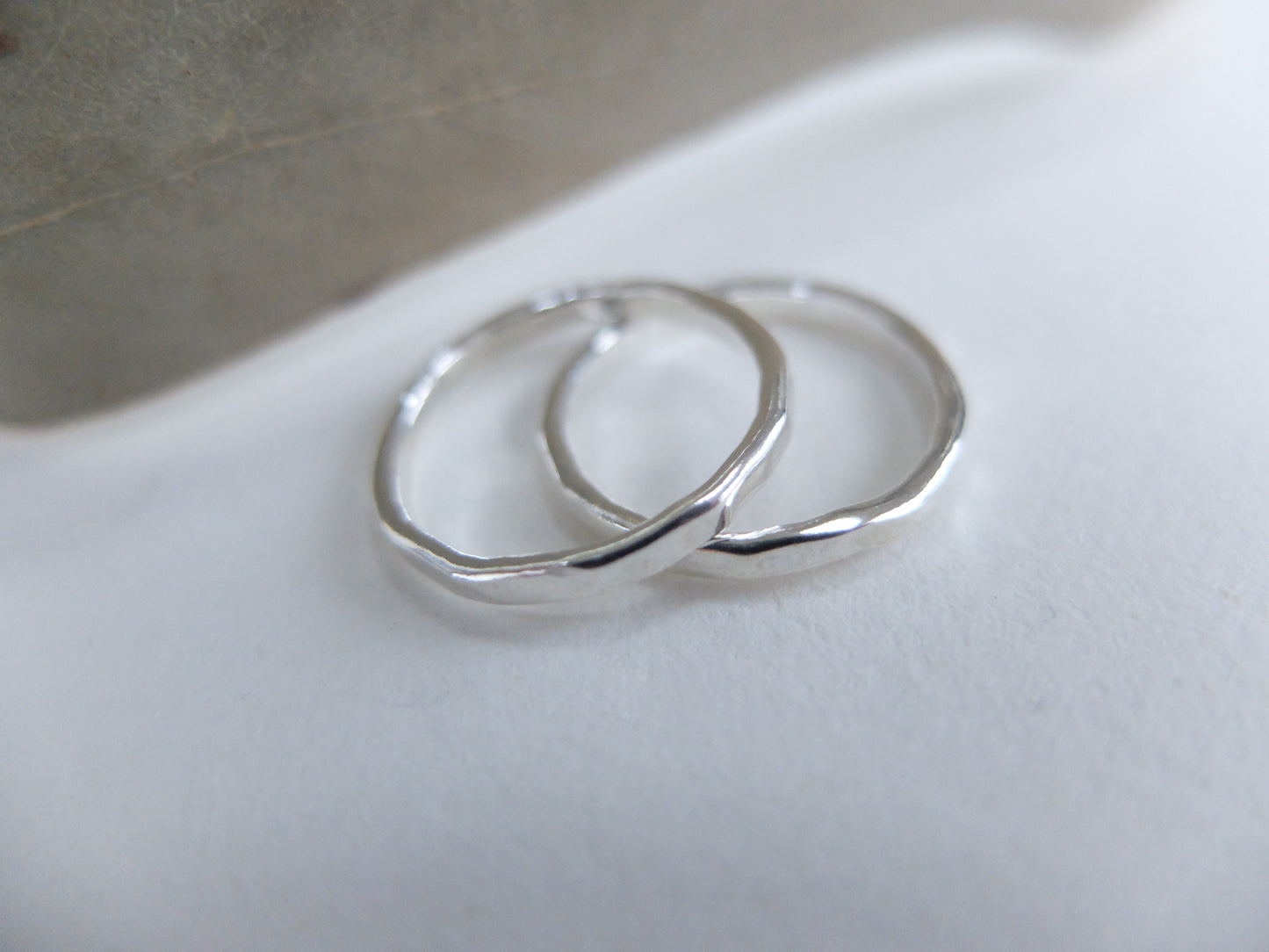 Two silver hoop earrings on a white surface with a neutral background