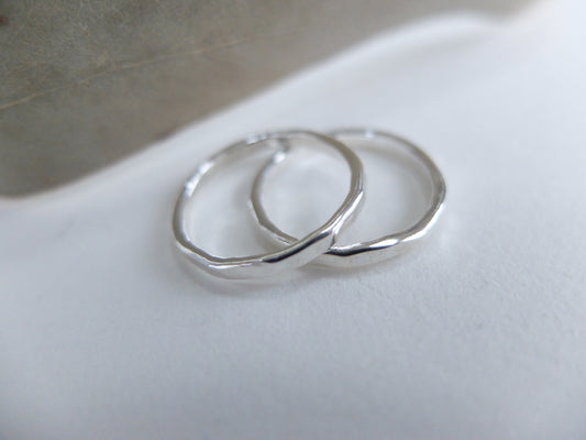 Two silver hoop earrings on a white surface with a neutral background