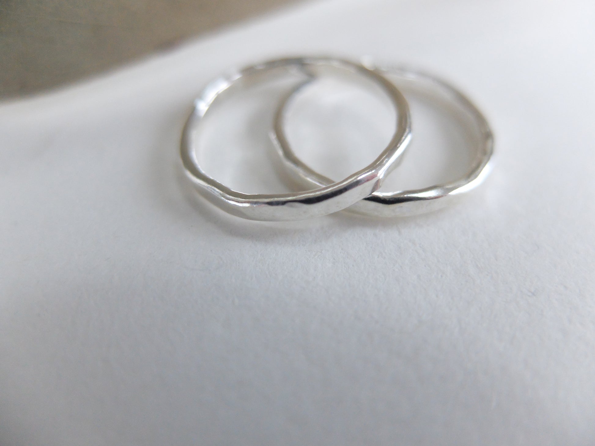 Two silver rings on a light gray surface