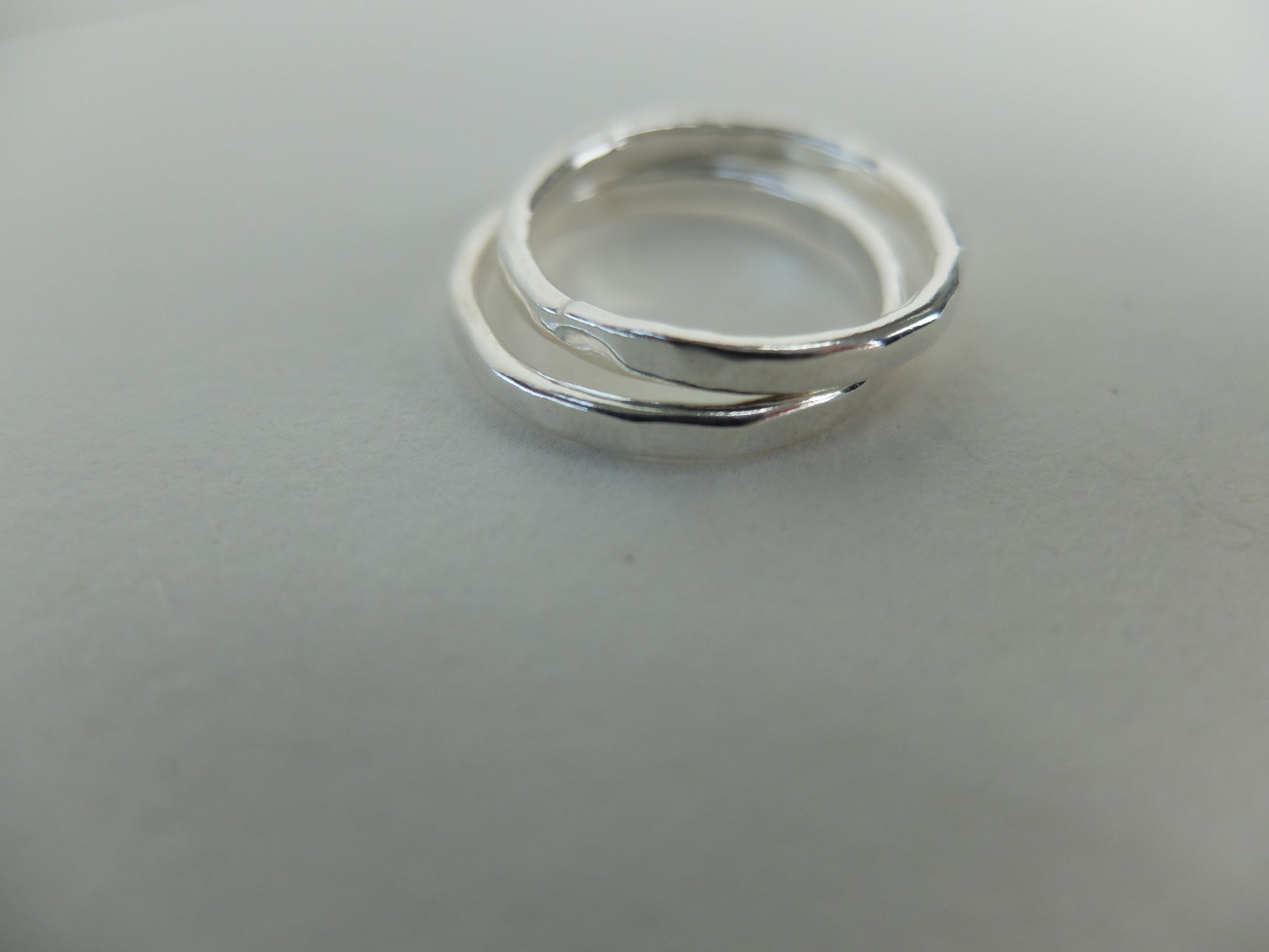 Two silver rings stacked on a light gray background
