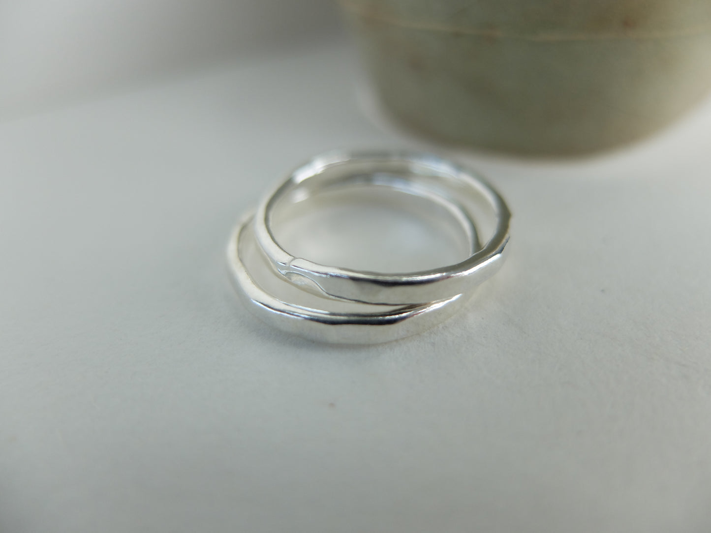 Two silver rings on a light gray surface