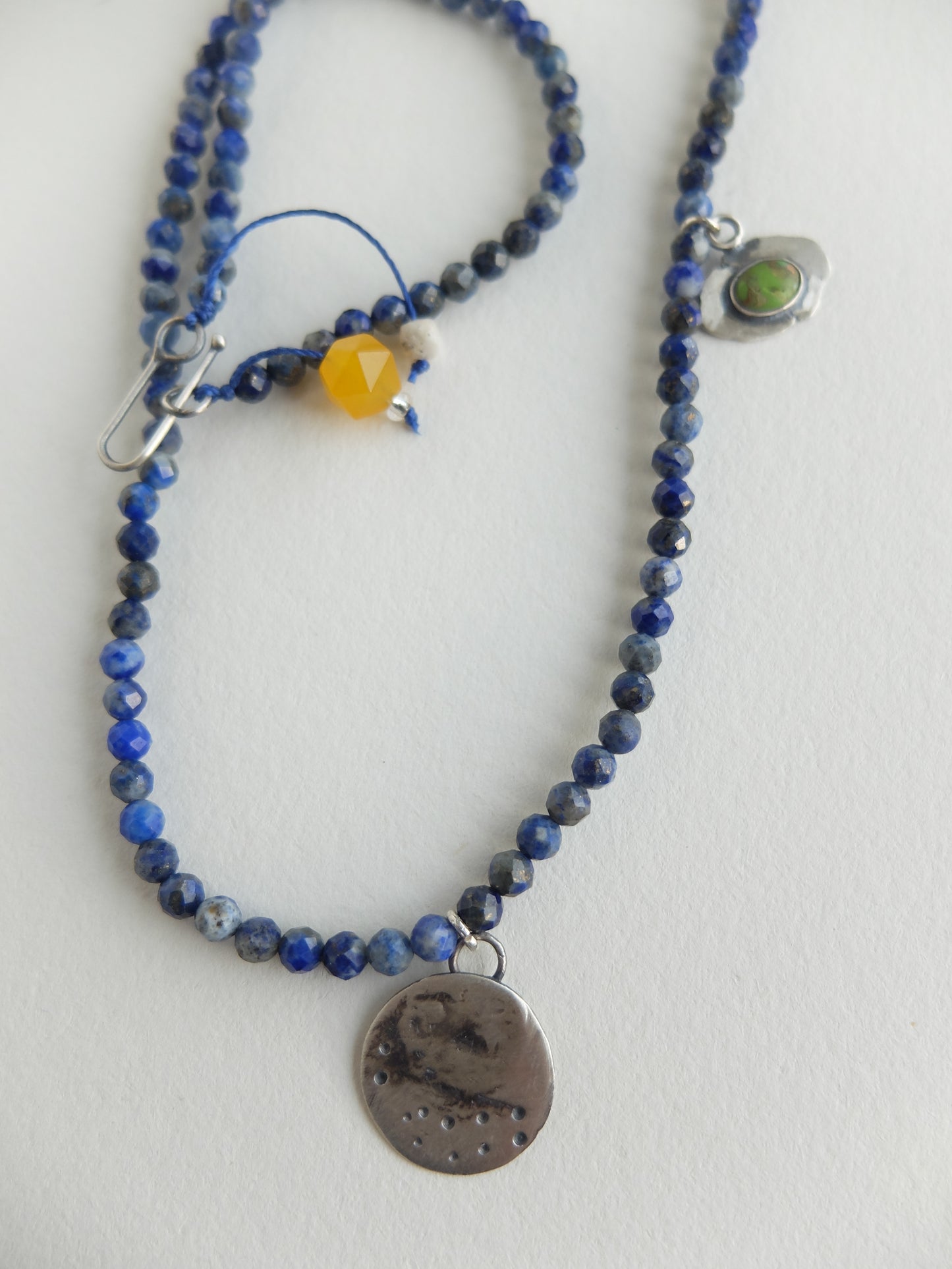 Blue faceted lapis lazuli  beaded necklace with decorative elements on a white background