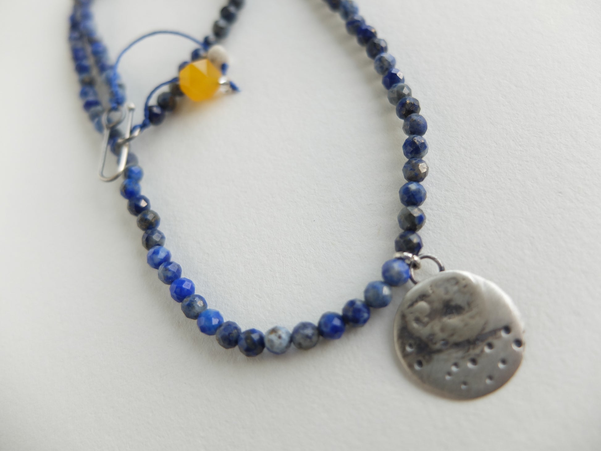 Necklace with blue beads and a silver pendant on a white background