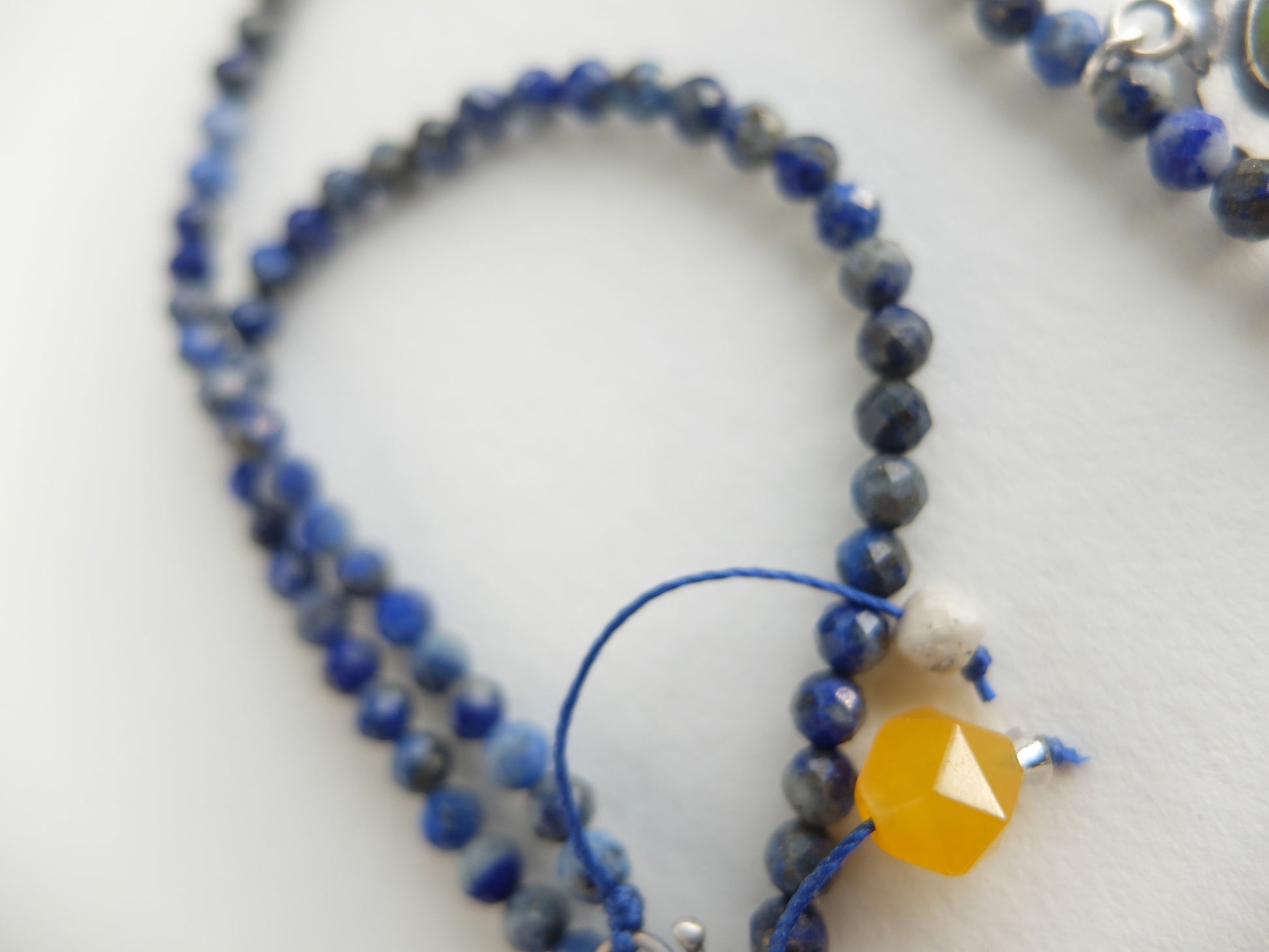 Close-up of a blue beaded necklace with a yellow pendant on a white background