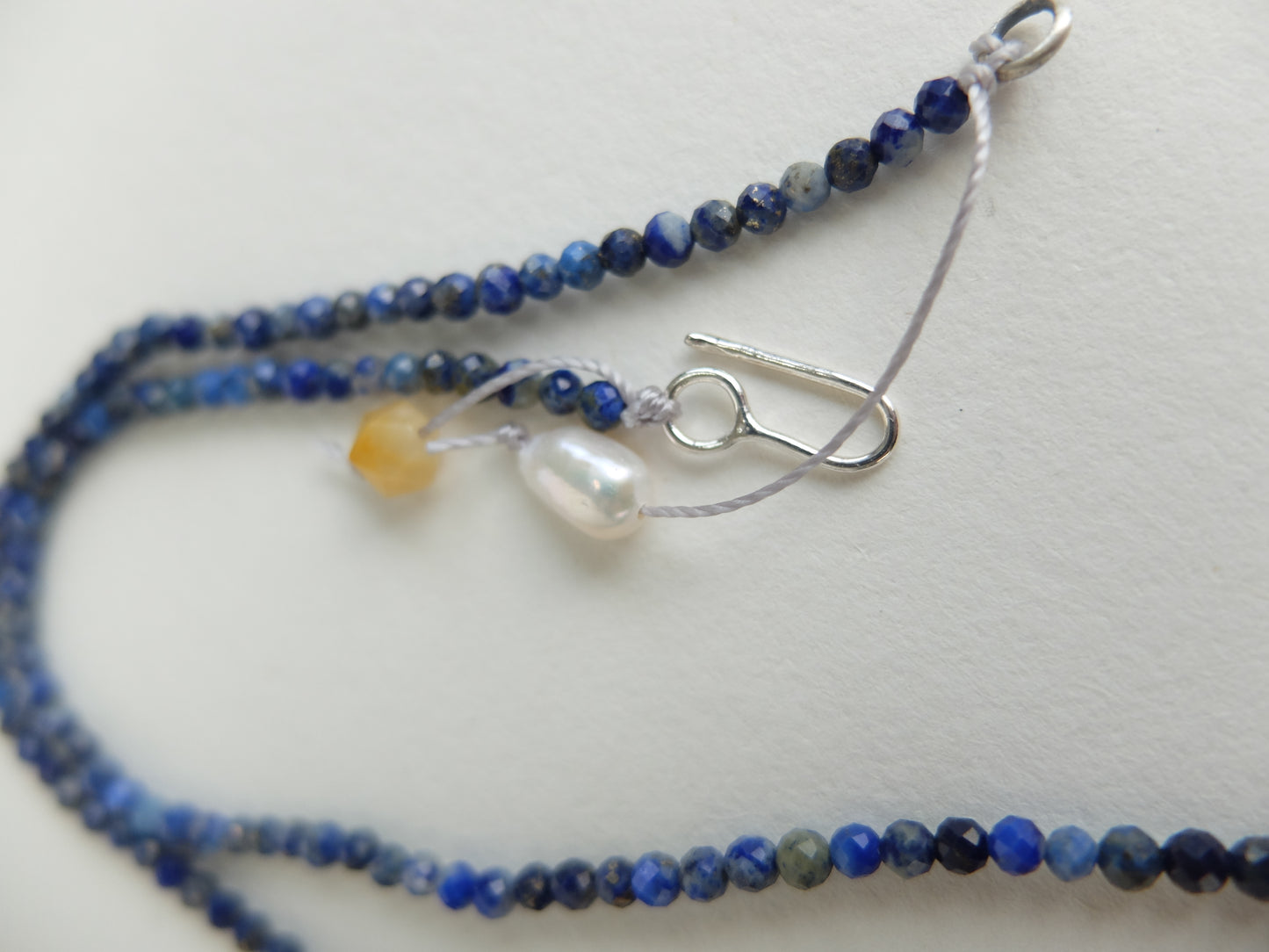 Blue beaded necklace with a silver clasp on a white background