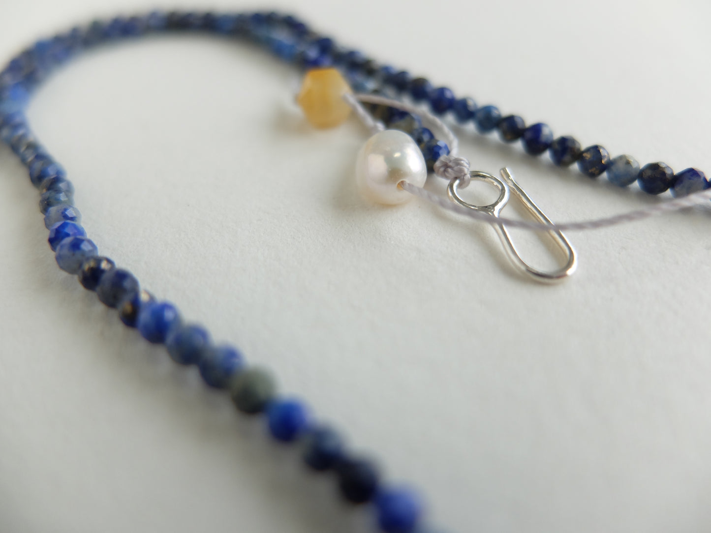 Necklace with blue beads and a silver clasp on a light background