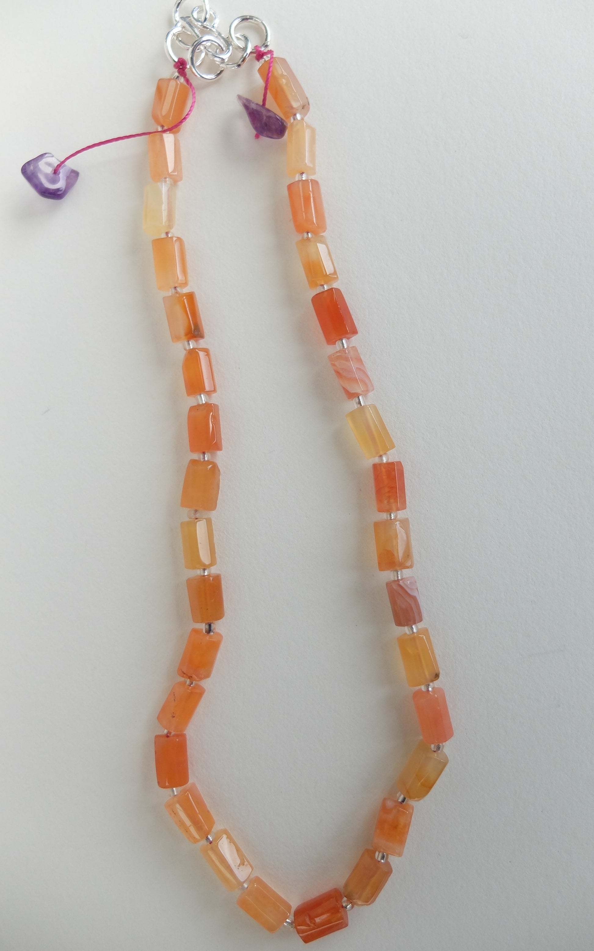 Necklace with orange red agate beads on a white background