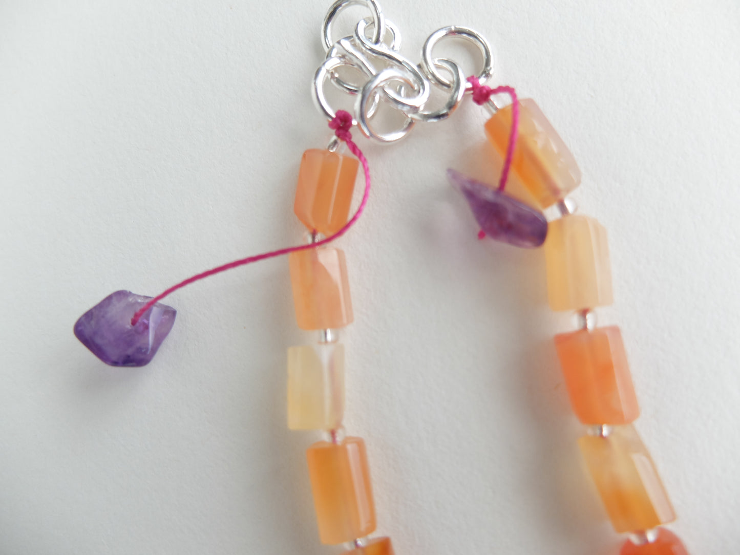 Beaded charm with orange and yellow beads and a silver clasp on a white background