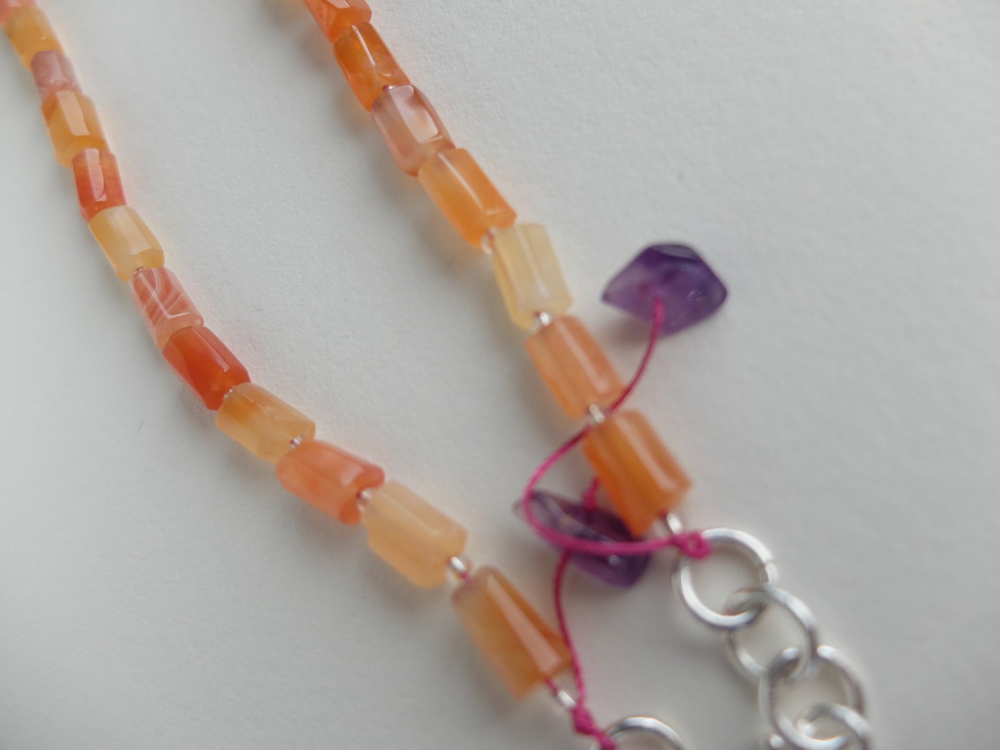 Necklace with orange beads and a silver clasp on a white background